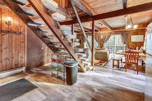 A rustic cabin interior with a wooden staircase, a dining area, and a cozy living space. - Hemlock Ridge 1D (Killington)