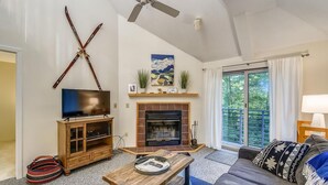 A living room with a fireplace, television, and sofa. - Woods Village 37 (Killington)