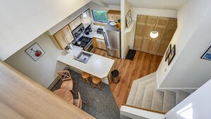 A compact kitchen with modern appliances, a dining area with a small table and chairs, and a staircase leading to another level. - Woods Village 37 (Killington)