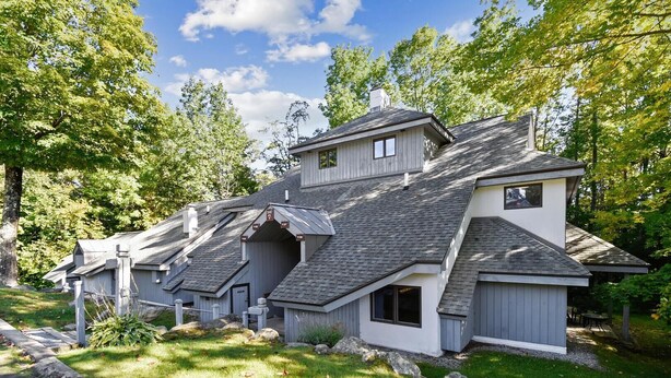 A modern house with a sloped roof, multiple levels, and a well-maintained garden. - Woods Village 37 (Killington)