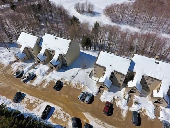 A parking lot with several cars and a building with a sloped roof.