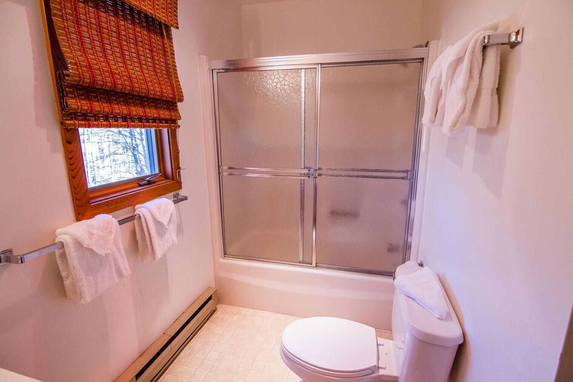 Un baño pequeño con ducha, inodoro y ventana con vistas.