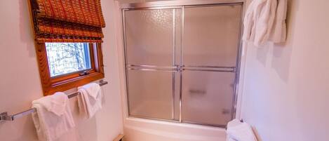 Un baño pequeño con ducha, inodoro y ventana con vistas.
