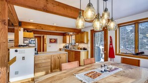Een moderne keuken met houten balken, een centraal eiland en hanglampen.