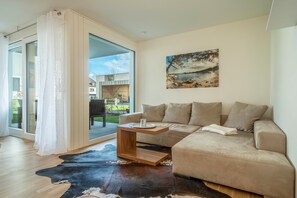 A modern living room with a beige sofa, a wooden coffee table, and a cowhide rug.