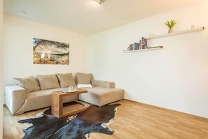 A living room with a sofa, a coffee table, a cowhide rug, a painting, and a bookshelf.