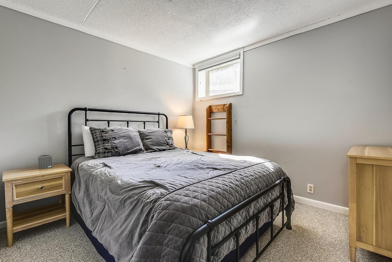 A bedroom with a bed, nightstand, and dresser.