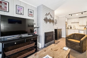 Una sala moderna con chimenea, televisor y un sillón acogedor.