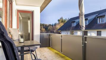 Ein Balkon mit Tisch und Stühlen, einer Tür und Blick auf benachbarte Häuser.