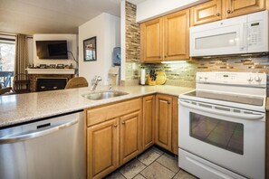 A modern kitchen with wooden cabinets, a granite countertop, a built-in microwave, and a stainless steel sink. - Pinnacle B20 (Killington)