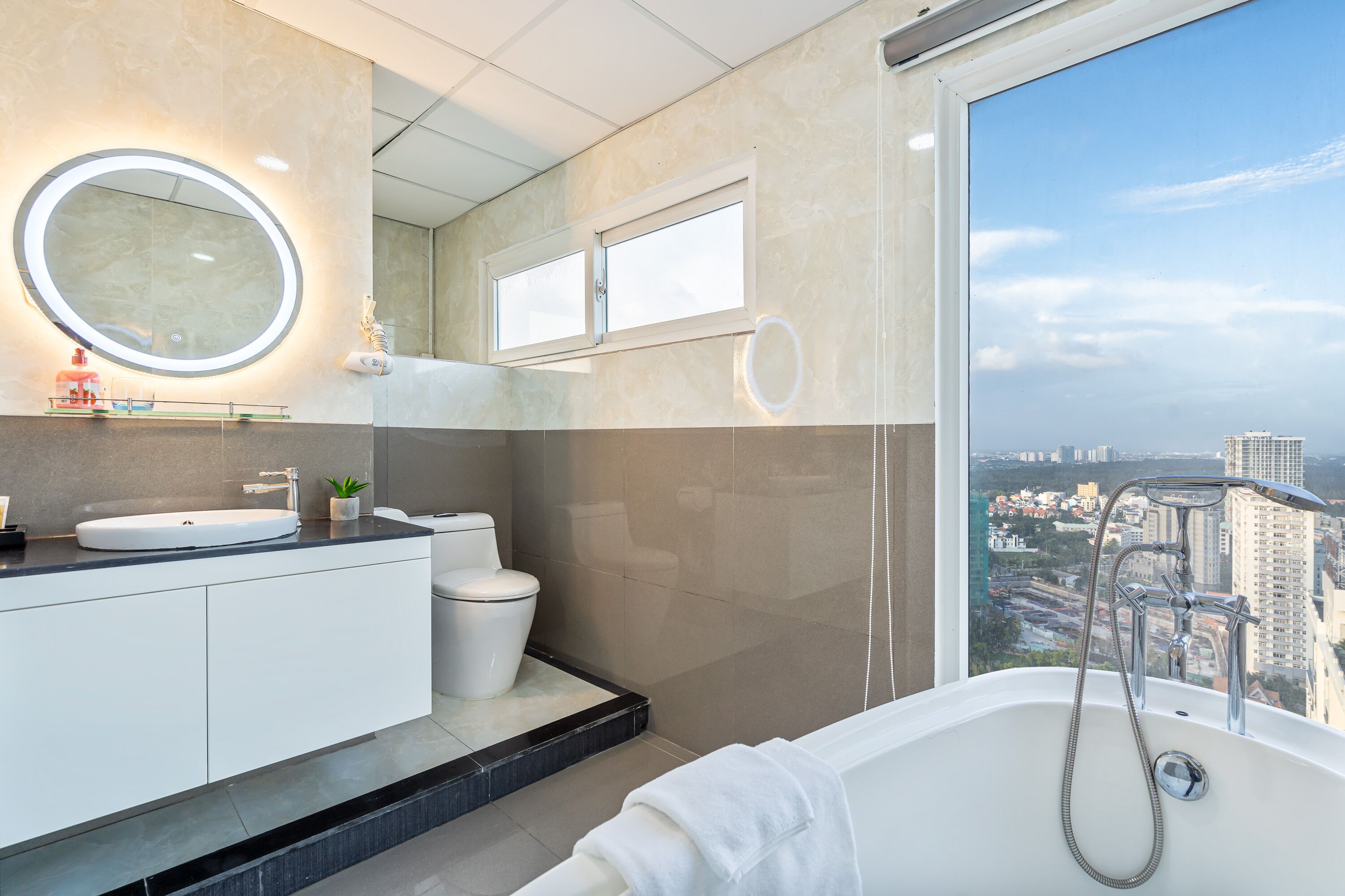 A modern bathroom with a bathtub, a sink, a toilet, and a large mirror.