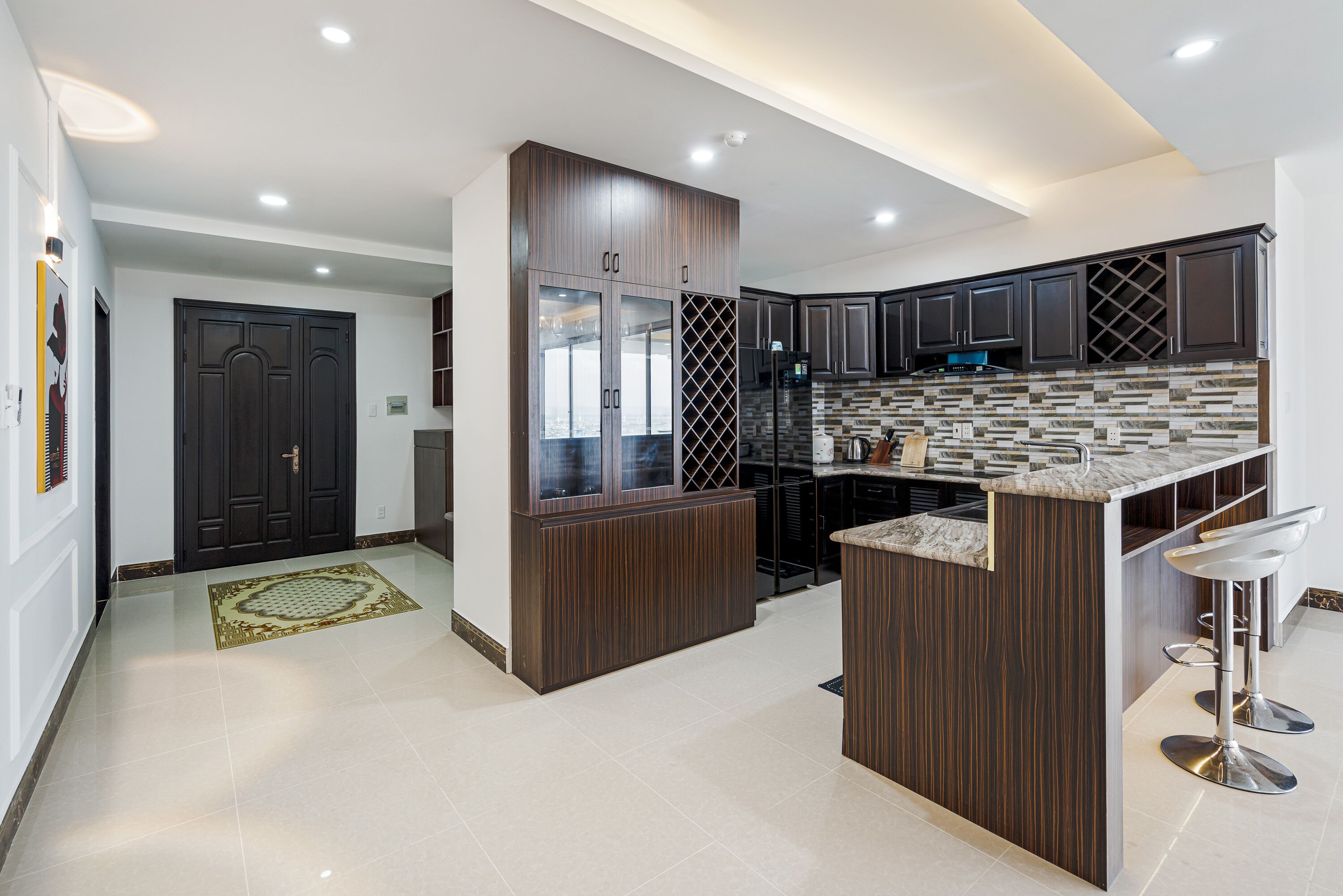 A modern kitchen with dark wood cabinets, a marble countertop, and a built-in wine rack.