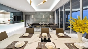 A modern kitchen with a central island, a dining area with a marble table, and a living area with a sofa and a large window. - Stephen Luxury Apartments (Ho Chi Minh City)