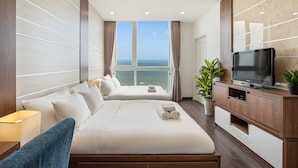 A hotel room with two beds, a TV, a plant, and a view of the sea. - Stephen Luxury Apartments (Ho Chi Minh City)