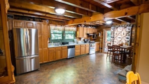 A spacious kitchen with wooden cabinets, a stainless steel refrigerator, and a dining area with a table and chairs.