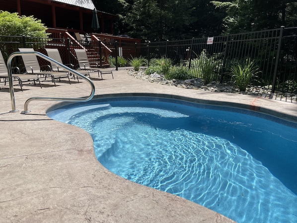 Una piscina con una escalera metálica, sillas de descanso y un letrero que dice 'No Diving'.