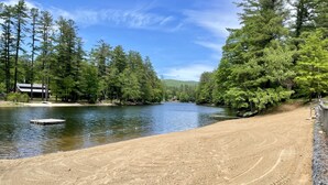 A sandy beach with a dock and a calm river.