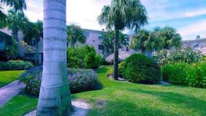 Un jardín cuidado con palmeras, una estructura de techo de paja y un letrero de propiedad privada.