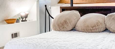 Ein Schlafzimmer mit weiß gestopfter Bettdecke, einem Holzkopfteil und einem Oberlicht.