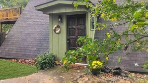 A house with a sloped roof, a green door, and a small porch area.
