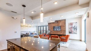 A modern kitchen with a large island, pendant lighting, and a seating area with orange chairs. - Abode at King's Crown, ski-in/ski-out, private hot tub, on private trail (Park City)