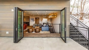 An open entrance to a modern interior with a staircase, seating area, and a view of the outdoors. - Abode at King's Crown, ski-in/ski-out, private hot tub, on private trail (Park City)