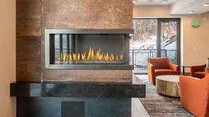 A modern interior with a fireplace, seating area, and a view through a glass door. - Abode at King's Crown, ski-in/ski-out, private hot tub, on private trail (Park City)