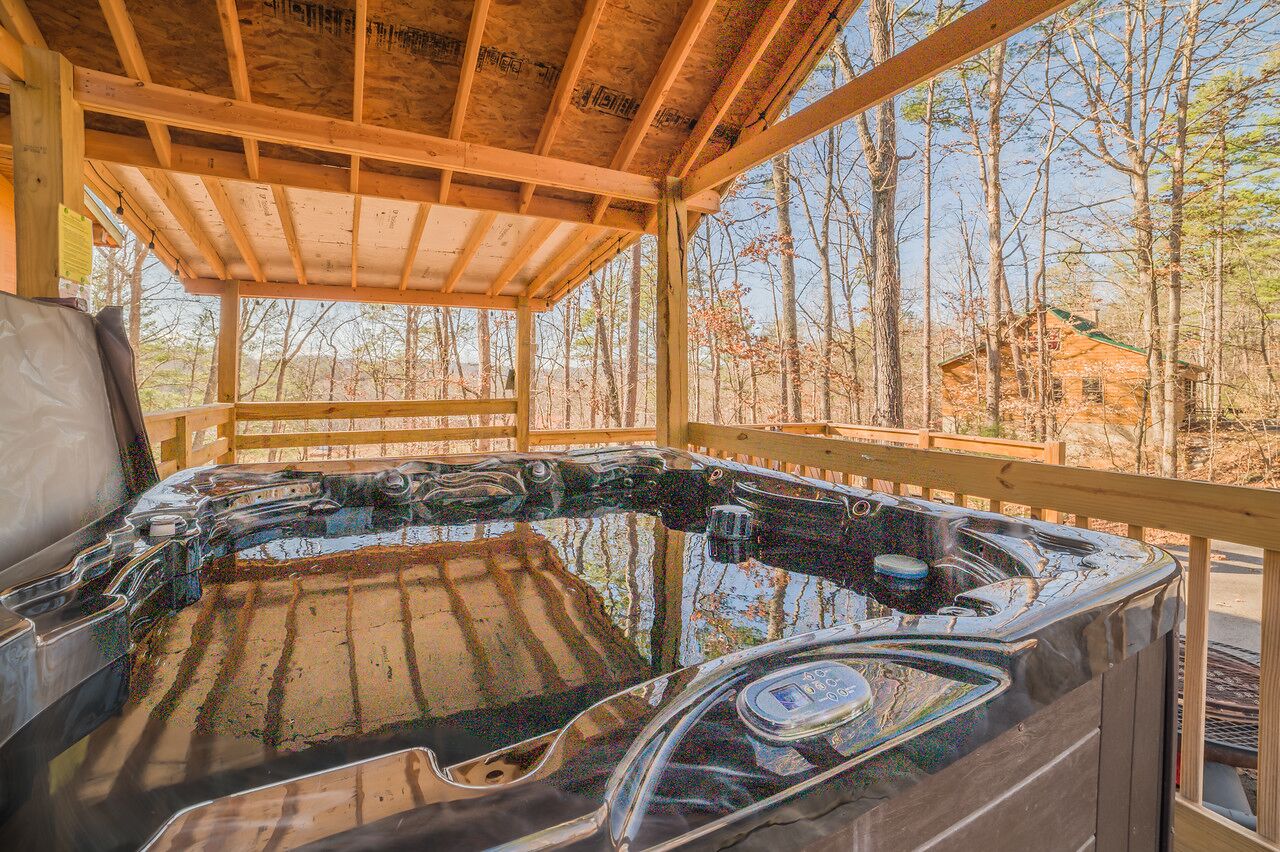 A hot tub with a wooden deck and a view of a forested area.