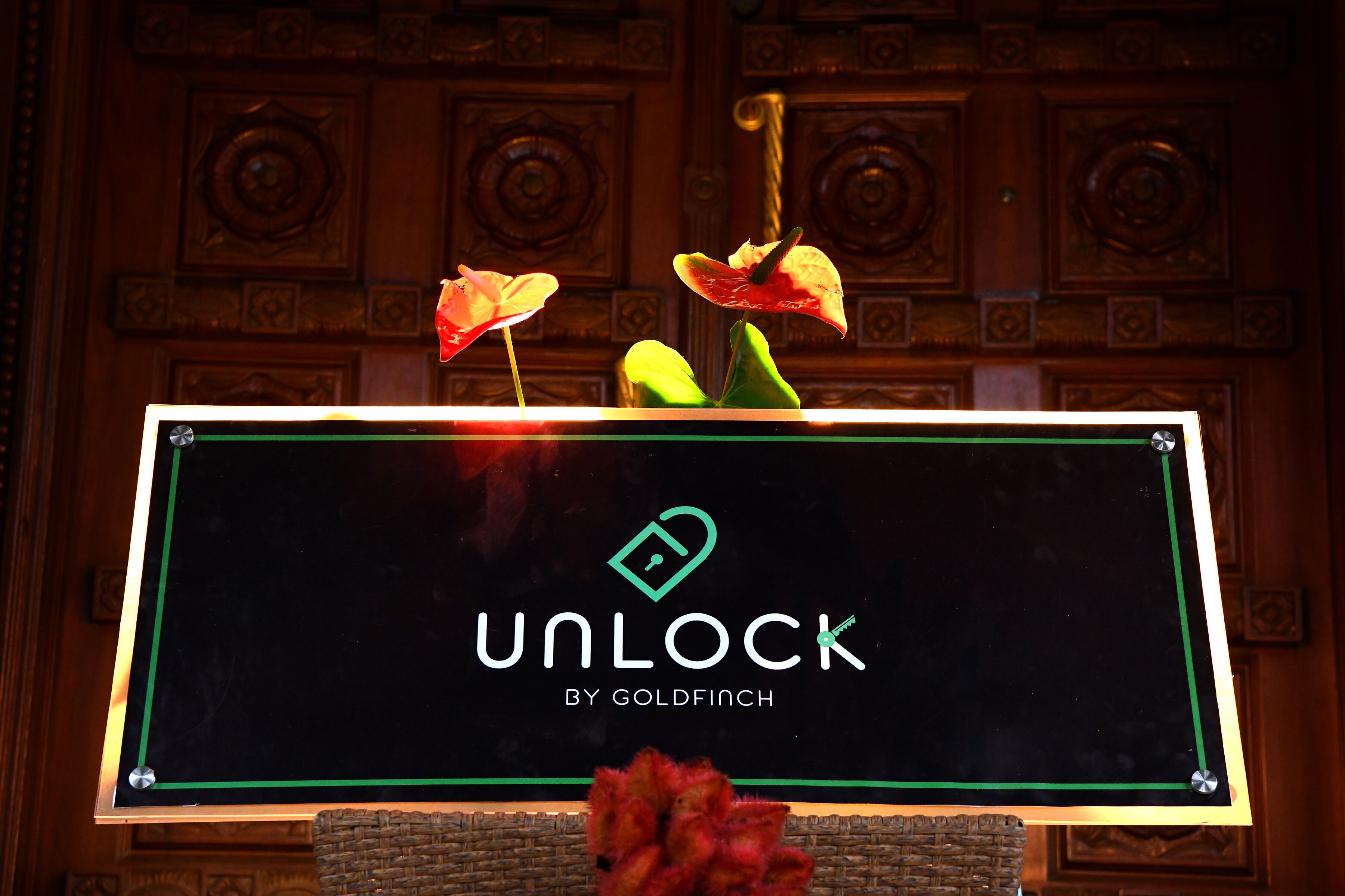 A sign with the text "UNLOCK BY GOLDFINCH" and decorative elements.