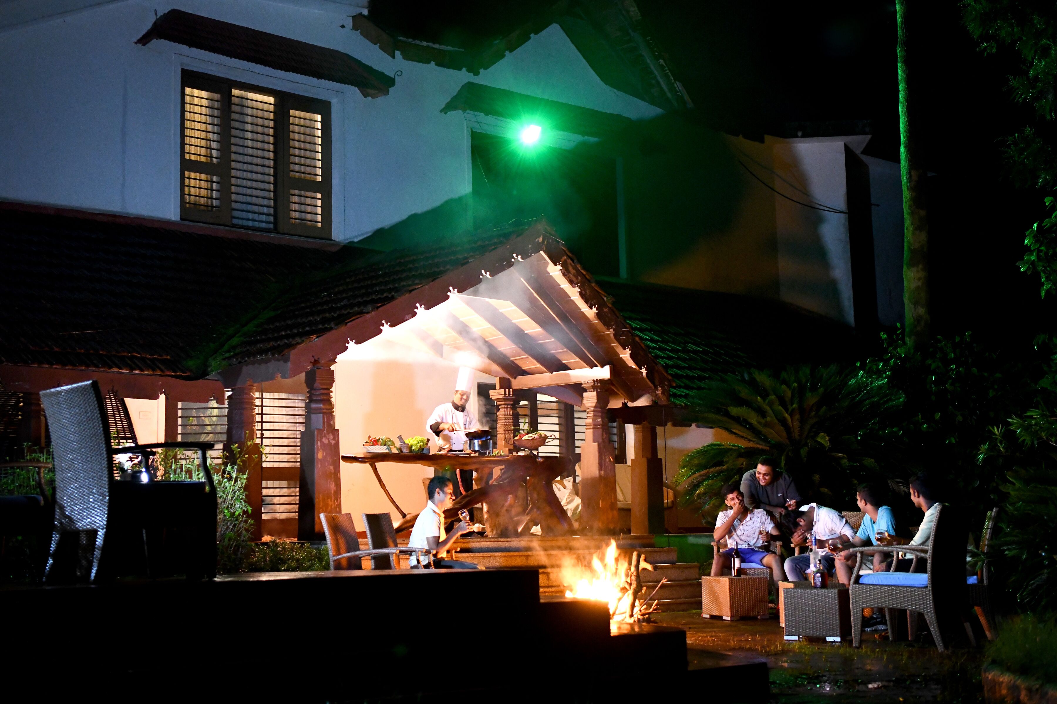 An outdoor dining area with a chef preparing food, surrounded by guests seated at tables.