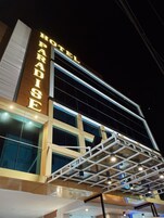Um hotel chamado "Paradise", com design arquitetônico moderno, apresentando uma placa chamativa e fachada de vidro.
