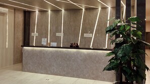 A reception area with a marble counter, overhead lighting, and a potted plant. - Paradise by CaLia Tarakan (Tarakan)