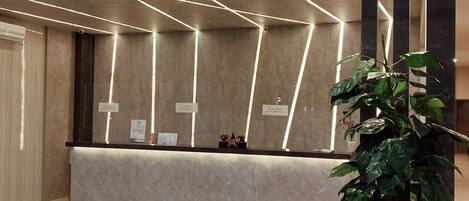 Una zona de recepción con mostrador de mármol, iluminación empotrada y una planta en maceta.