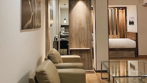 A modern hotel room with a sofa, a glass coffee table, and a wooden accent wall. - Paradise by CaLia Tarakan (Tarakan)