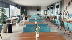 A spacious conference room with long tables and blue chairs, large windows, and a modern design. - Paradise by CaLia Tarakan (Tarakan)
