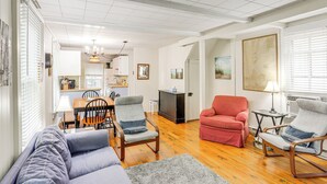 A spacious living room with a sofa, two armchairs, a dining area with a table and chairs, and a kitchen in the background. - Walk to Lake: Historic Lakeside Marblehead Cottage (Lakeside Marblehead)