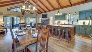 A spacious kitchen with wooden beams, a large island, and a dining area with a wooden table and chairs.