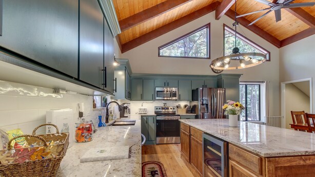 A spacious kitchen with dark cabinets, a large island, and a ceiling fan.