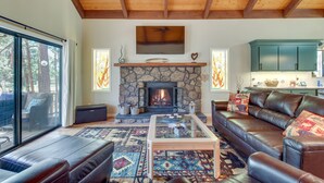 A cozy living room with a stone fireplace, leather sofa, and a glass coffee table.
