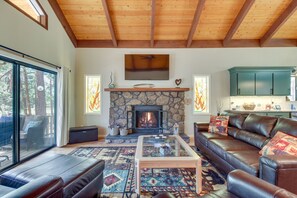 Una sala de estar acogedora con chimenea de piedra, sofá de cuero y una mesa de centro de vidrio.