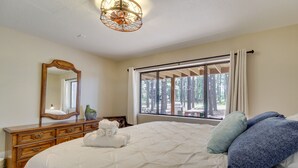 A bedroom with a large bed, a dresser, a mirror, and a window with curtains.