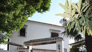 A white building with a stone facade, a tiled roof, and a covered entrance.