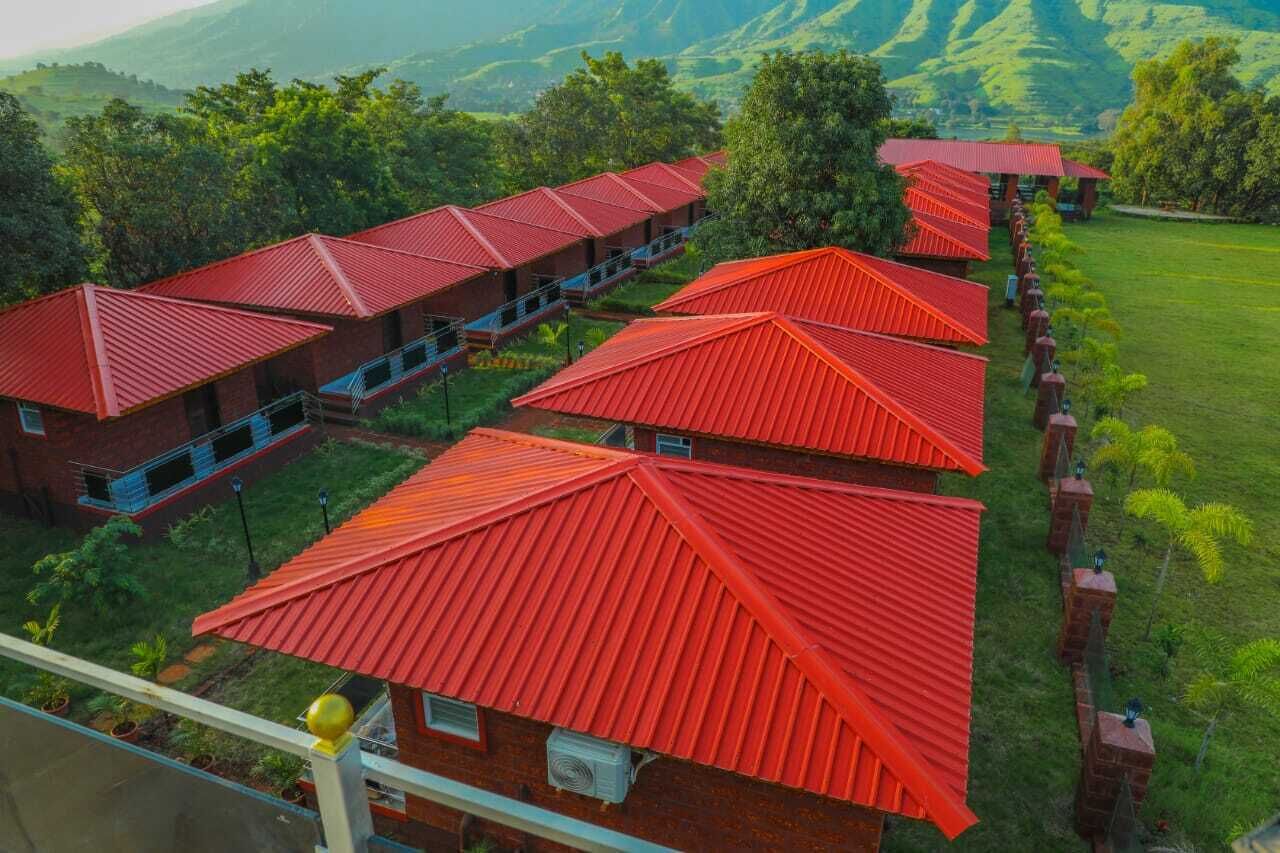 Une rangée de bâtiments aux toits rouges, offrant une vue dégagée sur le paysage verdoyant environnant et les collines lointaines.