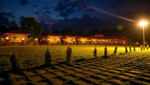 Filera d'edificis amb grans finestres i una zona enjardinada ben il·luminada.