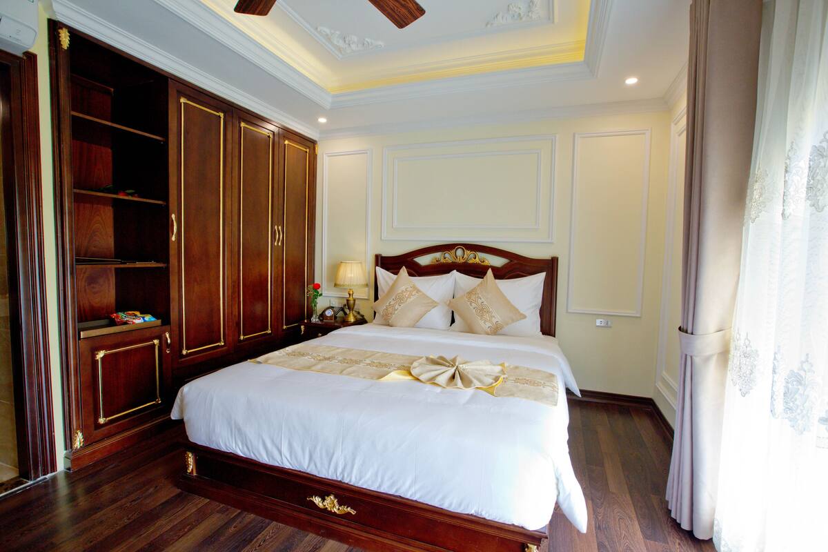 A large bed with a wooden headboard, a wardrobe with a mirror, and a nightstand with a lamp.