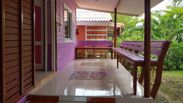 A covered outdoor area with a bench, a tiled floor, and a view of a garden. - OYO 75352 Hotel Family House And Resort Phetchaburi (Tha Yang)