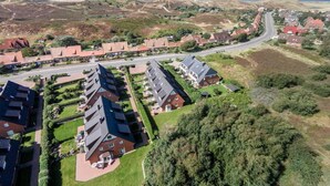 Een woonwijk met huizen, een weg en een glooiend landschap.