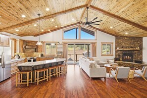 A spacious kitchen with a large island, a dining area with a fireplace, and a living room with a high ceiling and large windows. - Located in Moonridge Near Skiing, Golfing, Hiking, & Zoo! Views! Central A/C! HOT TUB! Pool Table, Shuffleboard & Foosball! (Big Bear Lake)