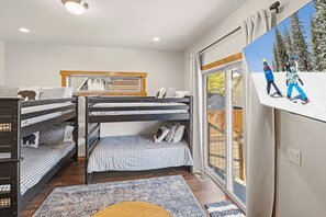 Une chambre avec des lits superposés, une fenêtre donnant sur les arbres et un tableau accroché au mur.