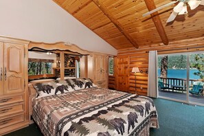 Une chambre dans un chalet en rondins, avec un grand lit, une armoire en bois et une vue sur l’ext érieur.